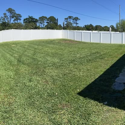 Clean mowed backyard with white vinyl fence